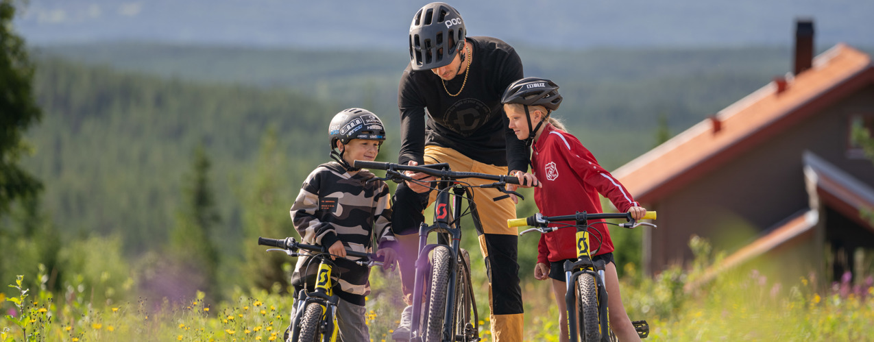 Familj cyklar MTB med vy över Orsasjön - upplevelserika turer i Orsa Grönklitt.