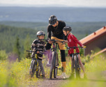 Familj cyklar MTB med vy över Orsasjön - upplevelserika turer i Orsa Grönklitt.