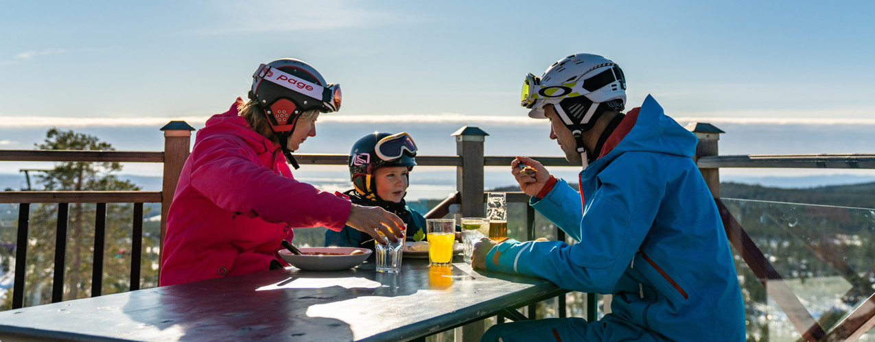 Familj som äter lunch på uteserveringen på Toppstugan i Orsa Grönklitt