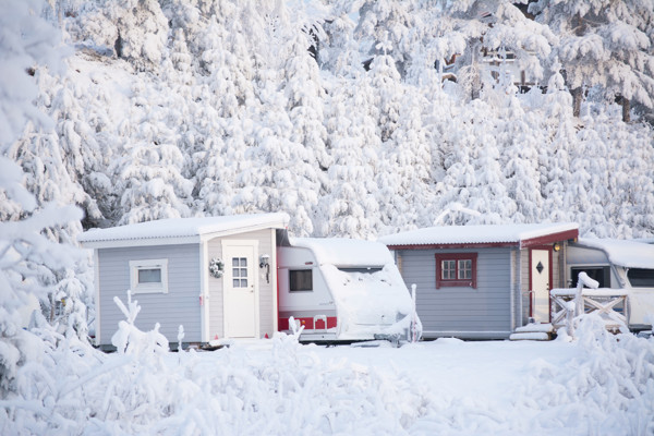Husvagn i vackert snölandskap med granar bakom