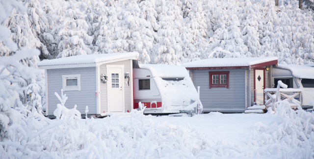 Husvagn i vackert snölandskap med granar bakom