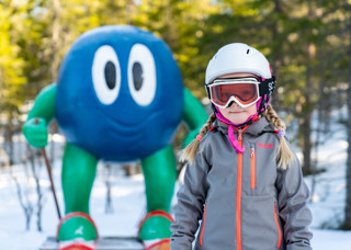 Flicka i alpinutrustning med Bärra Blåbär i bakgrunden