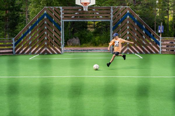 Ung pojke skjuter iväg fotboll på bollsportarenan - sportglädje i Orsa Grönklitt