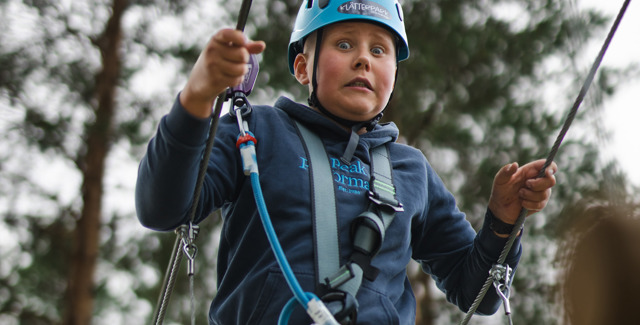 Ung pojke utmanar sin höjdrädsla i Klätterparken, Orsa Grönklitt.