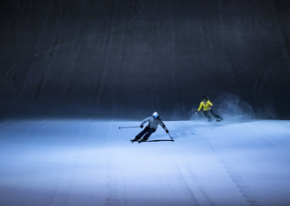 Slalomåkare i alpinbacke som åker i mörkret