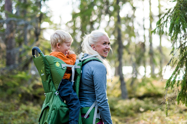 Ung mamma som vandrar med ett barn i bärväska på ryggen i Orsa Grönklitt.