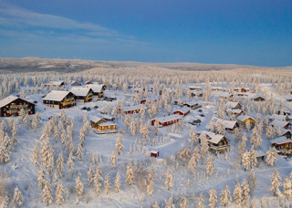 Vintrigt snötäckt landskap med stugor och granar - idylliskt vinterparadis i Orsa Grönklitt