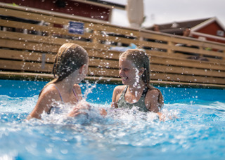 Två glada flickor leker i den uppvärmda poolen på Orsa Grönklitt - en rolig och avkopplande stund i vattnet.