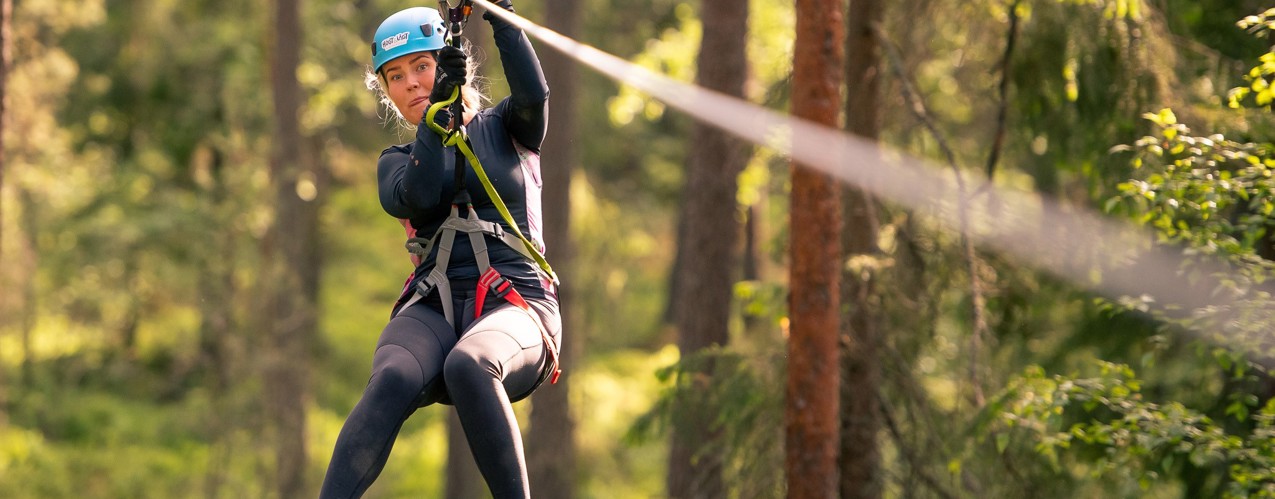 Kvinna åker Zipline i klätterpaken i Orsa Grönklitt