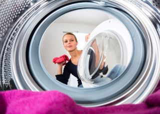 Kvinna som lägger in tvätt i tvättmaskin