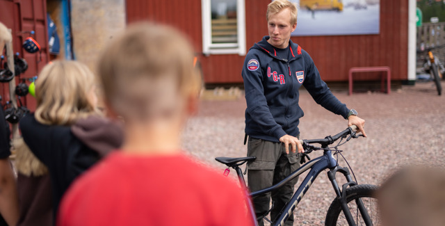 Anställd visar hyrcyklar för barn - redo för cykeläventyr i Orsa Grönklitt.
