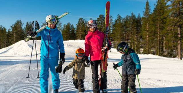 Familj i solig alpinbacke - gemensam skidåkning och njutning i Orsa Grönklitt.