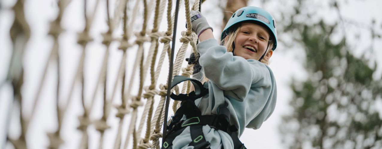 Flickebarn klättrar i nätet i Klätterparken, Orsa Grönklitt