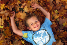 Pojke som ligger i en lövhög och njuter av hösten