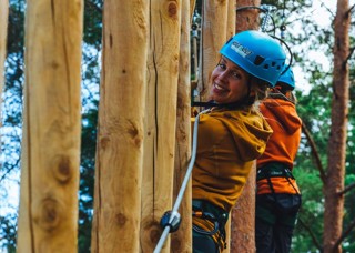 Kvinna som klättar i hinder i Grönklitts klätterpark