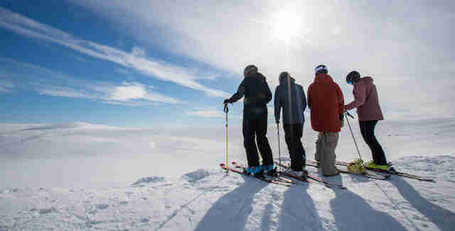 Kompisgäng som åker skidor står på fjället och njuter av utsikten över Tänndalen