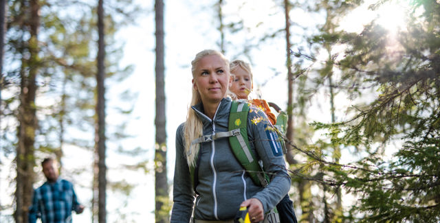 Kvinna som vandrar med barn i bärryggsäck i Orsa Grönklitt