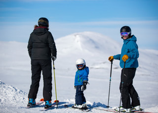 Familj på slalomskidor som tittar ut över fjäll